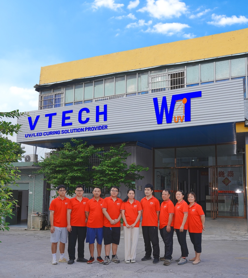 wtjd team The image shows a group of people in red shirts standing in front of a building. The building has a sign that says "VTECH UV/LED CURING SOLUTION PROVIDER".