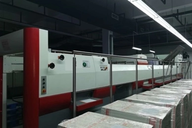 Wtjd-Lnkjet/Logo-Printing-LED-Installation Wtjd The image shows a large, automated bookbinding machine in a factory. The machine is surrounded by stacks of paper and books.